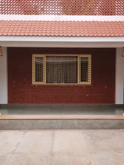 The central courtyard of the 'Grid in the Grove' farmhouse. This space features traditional wooden pillars and a terracotta tile roof, creating a cool and shaded area that is open to the sky.