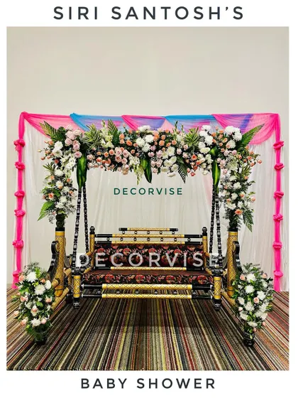 The traditional swing, or jhoola, is the heart of many baby showers. Here, we've decorated it with beautiful arrangements of fresh roses and lilies, set against a simple draped backdrop to make the floral work stand out.