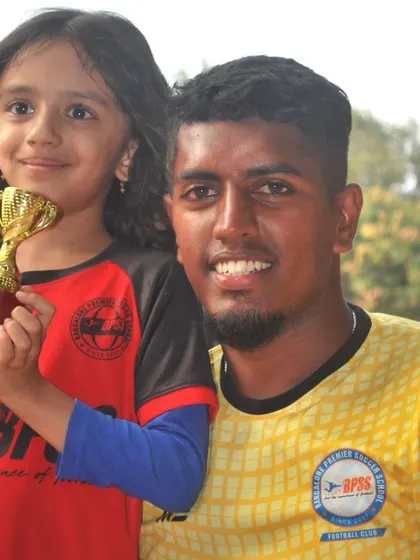 A young player from our girls' program proudly holds her trophy alongside one of our coaches. I am committed to providing equal opportunities and encouragement for all players.