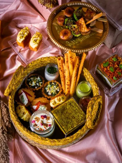 A closer look at a festive grazing platter, showcasing a mix of mini quiches, cheese straws, dips, and desserts, all beautifully arranged in a woven basket.
