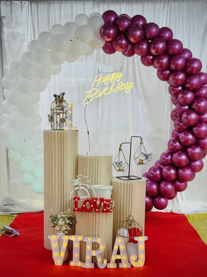 A simple and sweet birthday decoration with a half-arch of white and magenta balloons. This setup is perfect for outdoor or daytime events.