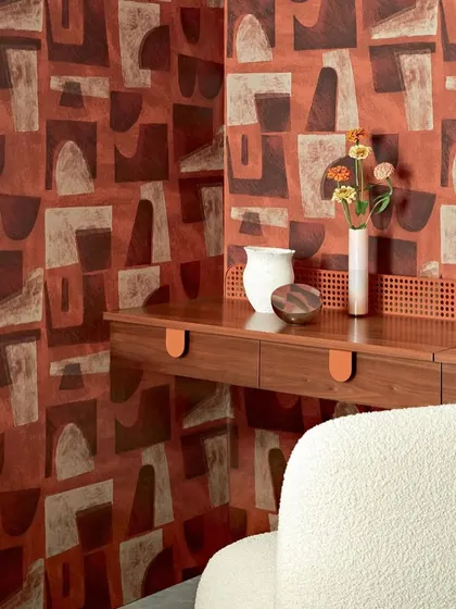 A full view of a room featuring the Élitis abstract wallpaper. The warm red tones and block-print style create a cozy yet modern atmosphere, demonstrating the wallcovering's ability to define a space.