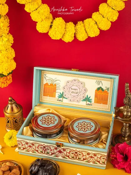 A beautiful blue and red patterned Diwali box against a bright yellow background with marigold garlands, creating a vibrant, festive mood.