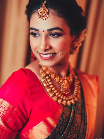 A lovely three-quarter portrait of the bride, her smile and beautiful gold jewelry shining in the warm light.