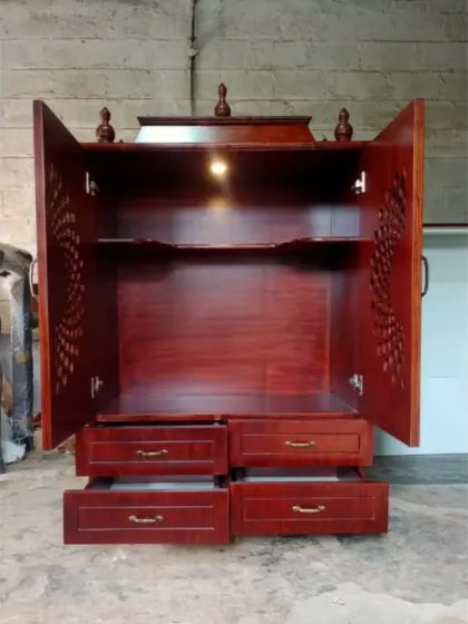 The mandir with its doors open and drawers pulled out, showcasing its full functionality. The warm light creates a serene and divine ambiance.