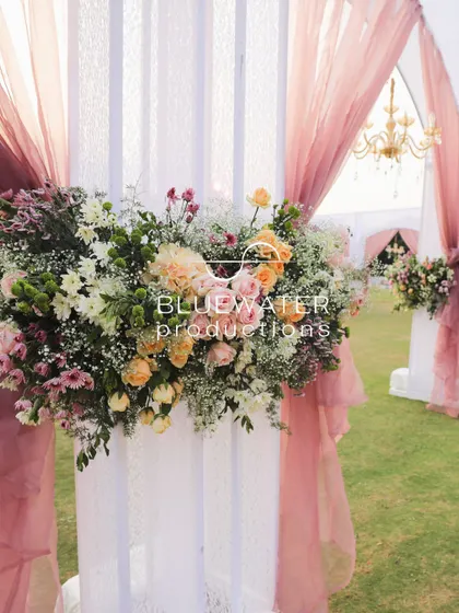A floral arrangement on a white pillar, draped with soft pink fabric, adds a romantic touch to the entrance.