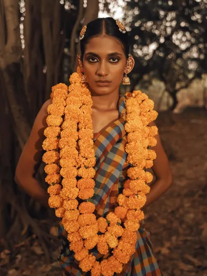 A powerful frontal shot where the model is adorned with heavy garlands of marigolds, creating a strong, culturally rich image.