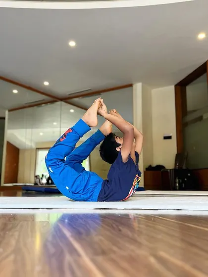 Good, better, best. Never let it rest. This young athlete works on his bow pose, a classic back-bending exercise to improve spinal flexibility.