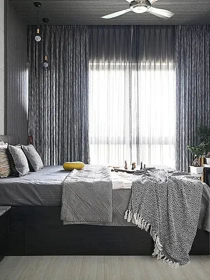 This bedroom showcases the power of a monochrome palette. We layered various shades and textures of grey, from the concrete-finish wall and fluted panels to the soft furnishings, creating a sophisticated and calming atmosphere that remains visually interesting.
