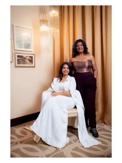 Standing proud next to a client wearing one of my white pant suit creations. I am wearing a custom brocade corset and trousers I designed. It shows the range of modern and fusion wear we can create for any event.