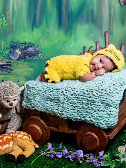 A sleepy baby dressed as a little tiger, resting on a cart in a magical forest. This is a sweet and peaceful take on a woodland-themed shoot.
