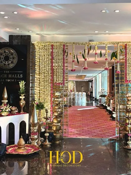 This wide entrance view shows how I combine multiple elements for a cohesive look. A floral welcome sign, traditional brass lamps, and a flower-draped archway come together to create a grand and inviting atmosphere.