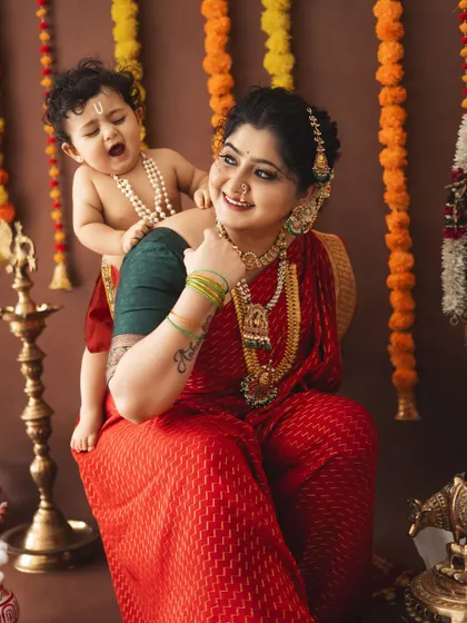 A playful baby Krishna yawns while sitting on his mother's back. These candid moments are priceless.