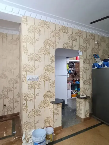 A living area with a repeating tree motif wallpaper, creating a warm and inviting atmosphere. The design complements the wooden door and flooring.
