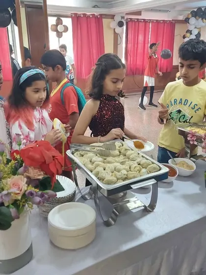 Kids enjoying the buffet at a birthday party. We ensure our food stations are accessible and filled with kid-friendly options like these delicious momos, so even the little ones can serve themselves and enjoy the meal.