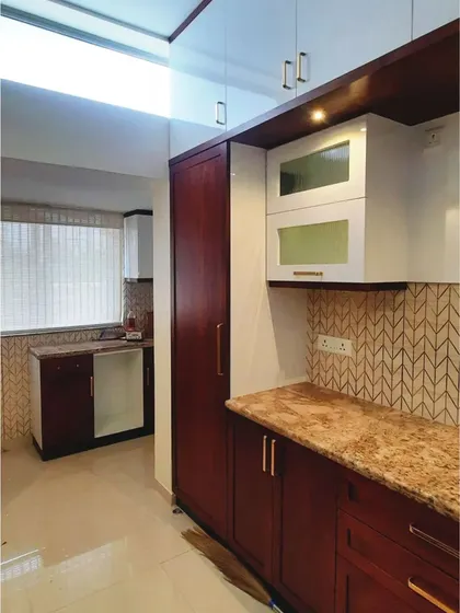 A view of the kitchen during installation, showing the combination of wood-finish and white cabinets, along with the tall pantry unit.
