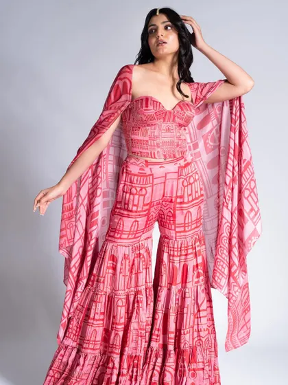 A beautiful pink and red ensemble paired with soft, glamorous makeup. The look features a subtle smokey eye and a neutral lip to balance the bold, printed outfit.