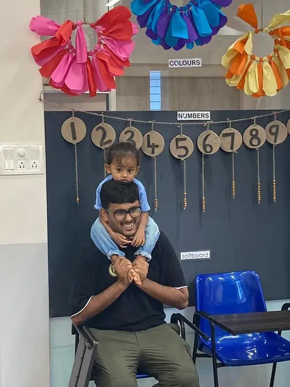 A father gives his child a shoulder ride in the classroom, a moment of pure joy. We create a fun and relaxed atmosphere where learning feels like play for both children and parents.