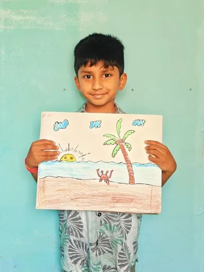 This student is all smiles with his completed drawing of a sunny day at the beach.