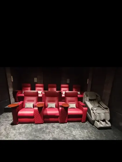 Comfort is key to the cinema experience. We provide custom seating solutions, including these plush, motorized red leather recliners, complete with cup holders and side tables for the ultimate convenience.