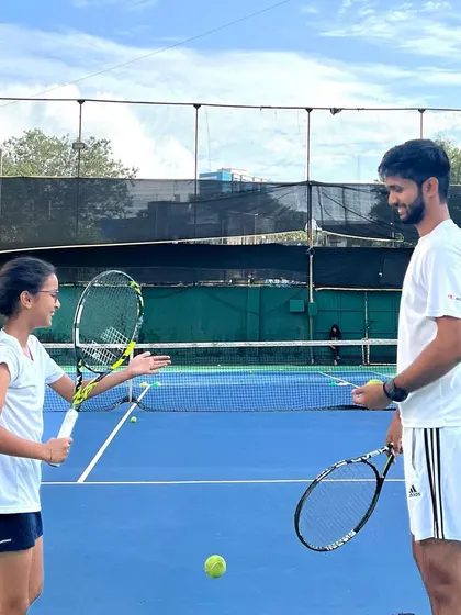 The relationship between a coach and a player is built on trust and communication. I believe in creating a positive environment where students feel understood and motivated. Here, I'm discussing technique with a young player during a training session.