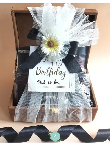 The final look of the "Dad to be" hamper. It's wrapped in delicate white tulle with a flower and a personal tag, making it look as good as it feels to receive.