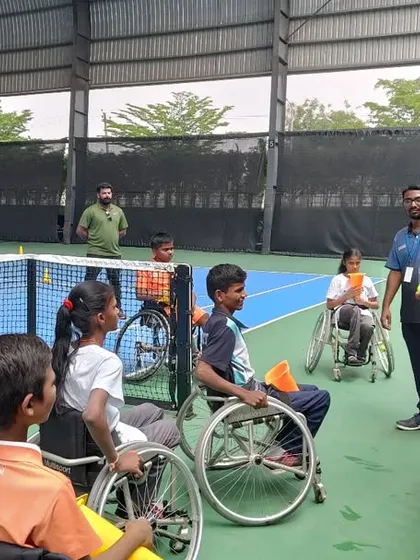 A coach gives hands-on instruction to young players during a kids' wheelchair tennis workshop. We focus on making the sport accessible and fun for beginners.