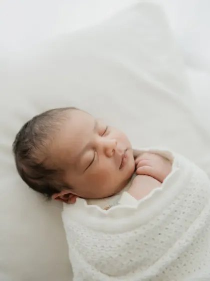 A close-up shot focusing on the newborn's serene face while swaddled. These simple portraits make for timeless family heirlooms.