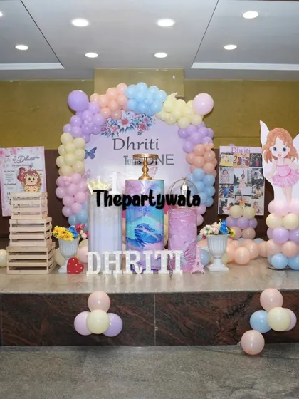 A full stage setup for a fairy and butterfly first birthday, with pastel balloons and character cutouts.