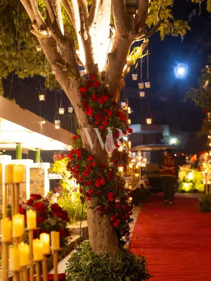 A tree wrapped in a spiral of red roses, with hanging candle votives creating a magical, twinkling effect. This is how I integrate natural elements into a luxurious design.