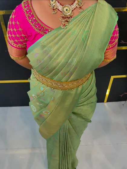 A close-up of the pre-pleated pastel green saree, showing the perfect, uniform pleats.