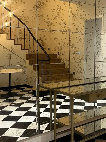 An antiqued mirror wall adds glamour and reflects light beautifully in this entryway. Paired with a checkerboard floor, it creates a bold and dramatic first impression.
