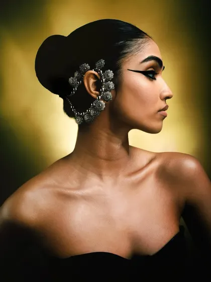A stunning beauty shot from the 'Silver Jewels of Bombay' series, focusing on a large, ornate silver ear cuff. The warm, diffused light and elegant pose highlight the craftsmanship of the traditional jewelry.