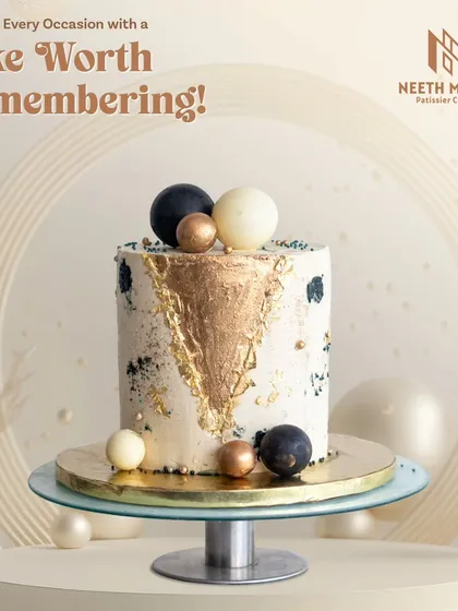 A cake worth remembering. This modern and artistic cake features a gold-leafed geometric pattern and is topped with black, white, and bronze chocolate spheres.