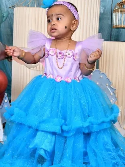 The birthday girl in her custom blue and lavender gown. The dress has a high-low hemline and floral details at the waist.