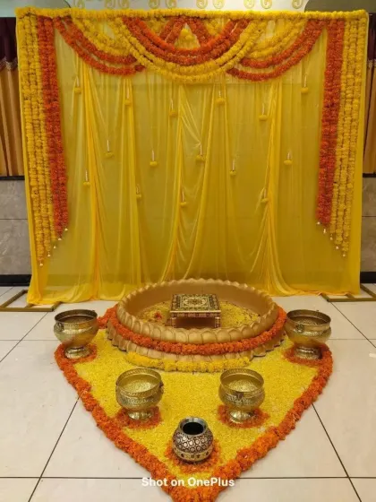 This is a classic Haldi ceremony setup, focusing on the ritual space. I used marigold petals to create a floral carpet, arranged traditional brassware, and framed it all with a bright yellow backdrop and marigold garlands.