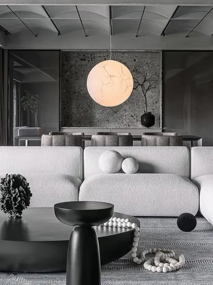 A view of the formal living room in the Vaulted Haus, where custom furniture pieces interact with the architectural elements. The low-profile sofa and sculptural coffee tables maintain a dialogue with the grand, vaulted ceiling, creating a cohesive and balanced monochromatic environment.
