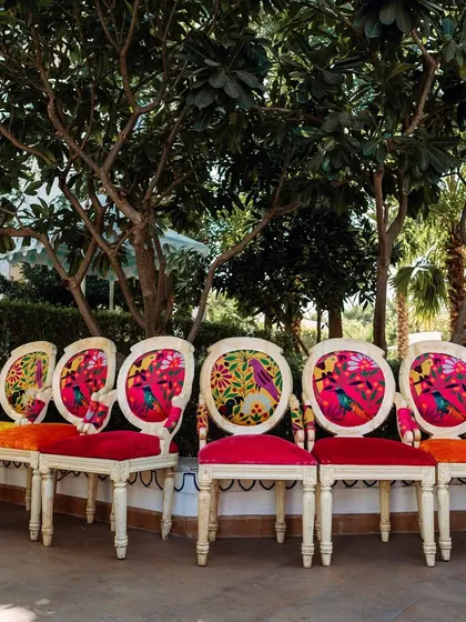 A row of custom chairs with vibrant, printed backs, adding another layer of detail to the eclectic Haldi decor.