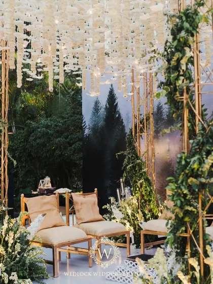 A closer look at the details of our minimalist forest-themed mandap. The structure is wrapped in lush greenery, with arrangements of white flowers and candles creating a romantic glow.