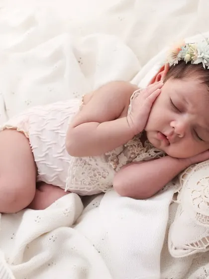 A little angel, dreaming sweetly. This newborn portrait with a delicate floral crown and soft, lacey outfit is all about capturing innocence. The simple, clean background keeps all the focus on your baby's serene beauty.