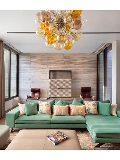 A comfortable seating area within the master suite of the Punjabi Bagh residence. The vibrant green sofa and a modern glass chandelier create a colorful and stylish corner for private relaxation.