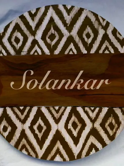 This circular nameplate in a rustic brown Ikat pattern is a perfect example of our bespoke work. We can adapt our designs to different color palettes to match your home's aesthetic.