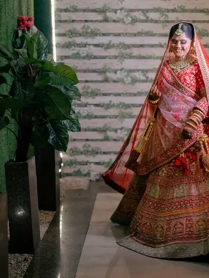 A full-length shot of the bride, her red veil flowing behind her. This image captures the grandeur and grace of the bridal look.