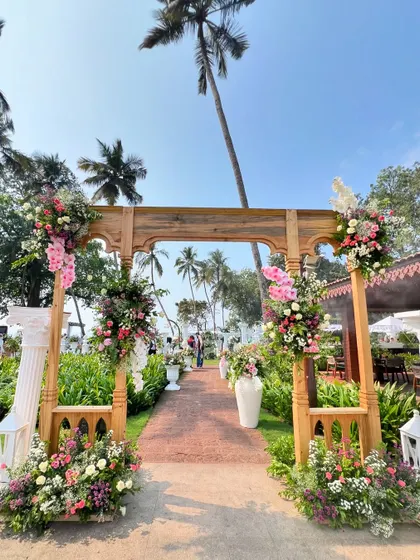 The grand entrance to our Roman-themed mehendi, with the wooden archway framing the path to the beachside celebration.