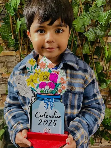 A proud student holding the 2025 calendar he finished in our New Year's workshop.