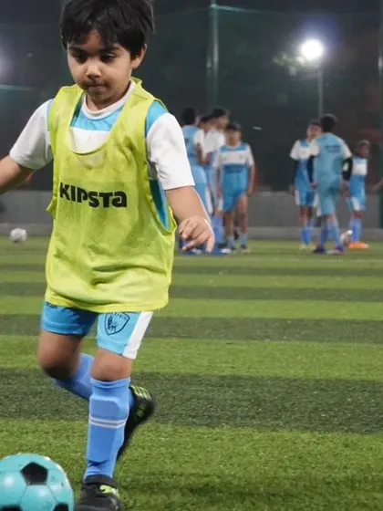 A toddler in a training bib dribbles the ball, showing that it's never too early to start learning the fundamentals.