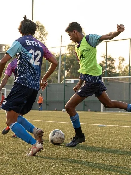 Two players battling for the ball during a training match, showing the competitive fire we nurture.