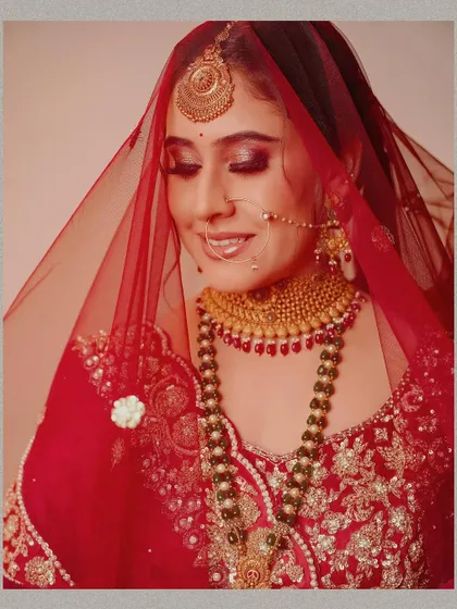 A close-up portrait of the bride under her red veil. The soft focus and her gentle smile create a classic, romantic, and timeless bridal image.
