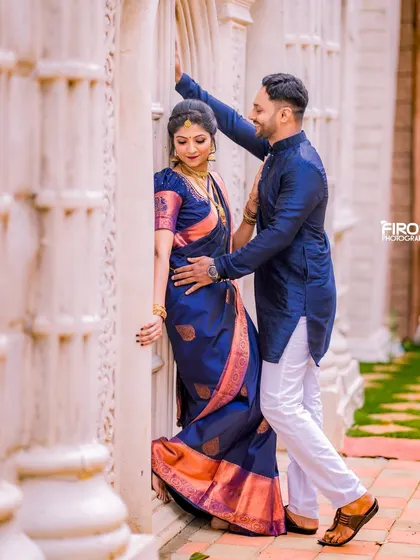 A romantic pose against a backdrop of white pillars. The deep blue of the couple's outfits creates a striking contrast, making for a very elegant portrait.