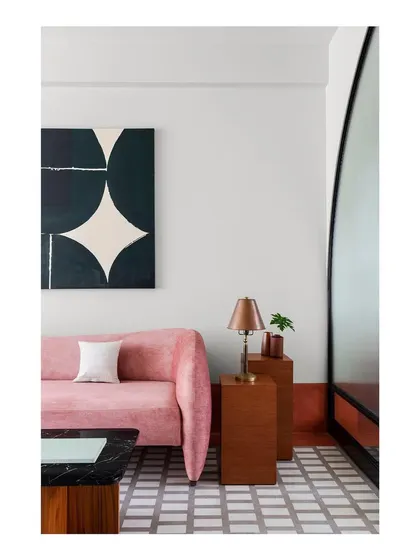 A vignette from the family lounge, showing the interplay of color, form, and material. The custom pink sofa, geometric floor, and dark wood side tables create a composition of smaller, interesting spatial moments.
